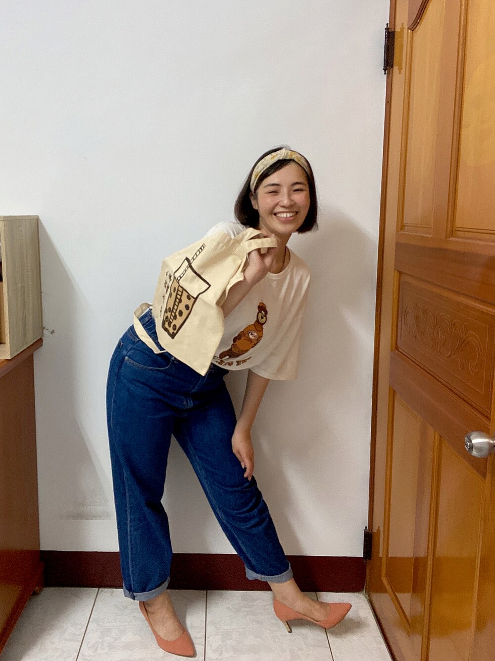 ブルー系のデニムパンツ、ベージュ系のショルダーバッグ、オレンジ系のパンプスを着用したレディースの夏コーディネートの2枚目の写真