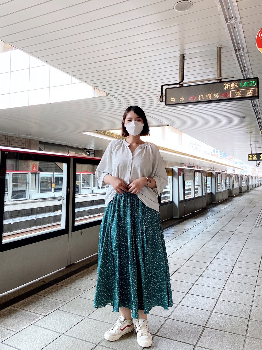 グリーン系のアンサンブル、グリーン系のスカート、ベージュ系のスニーカーを着用したレディースの夏コーディネートの2枚目の写真