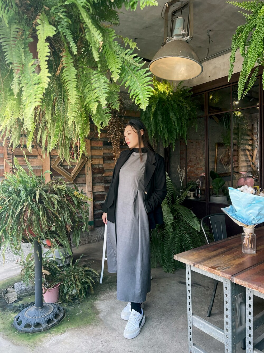 グレー系のジャンパースカート、ブラック系のテーラードジャケット、ホワイト系のシューズを着用したレディースの春コーディネートの2枚目の写真