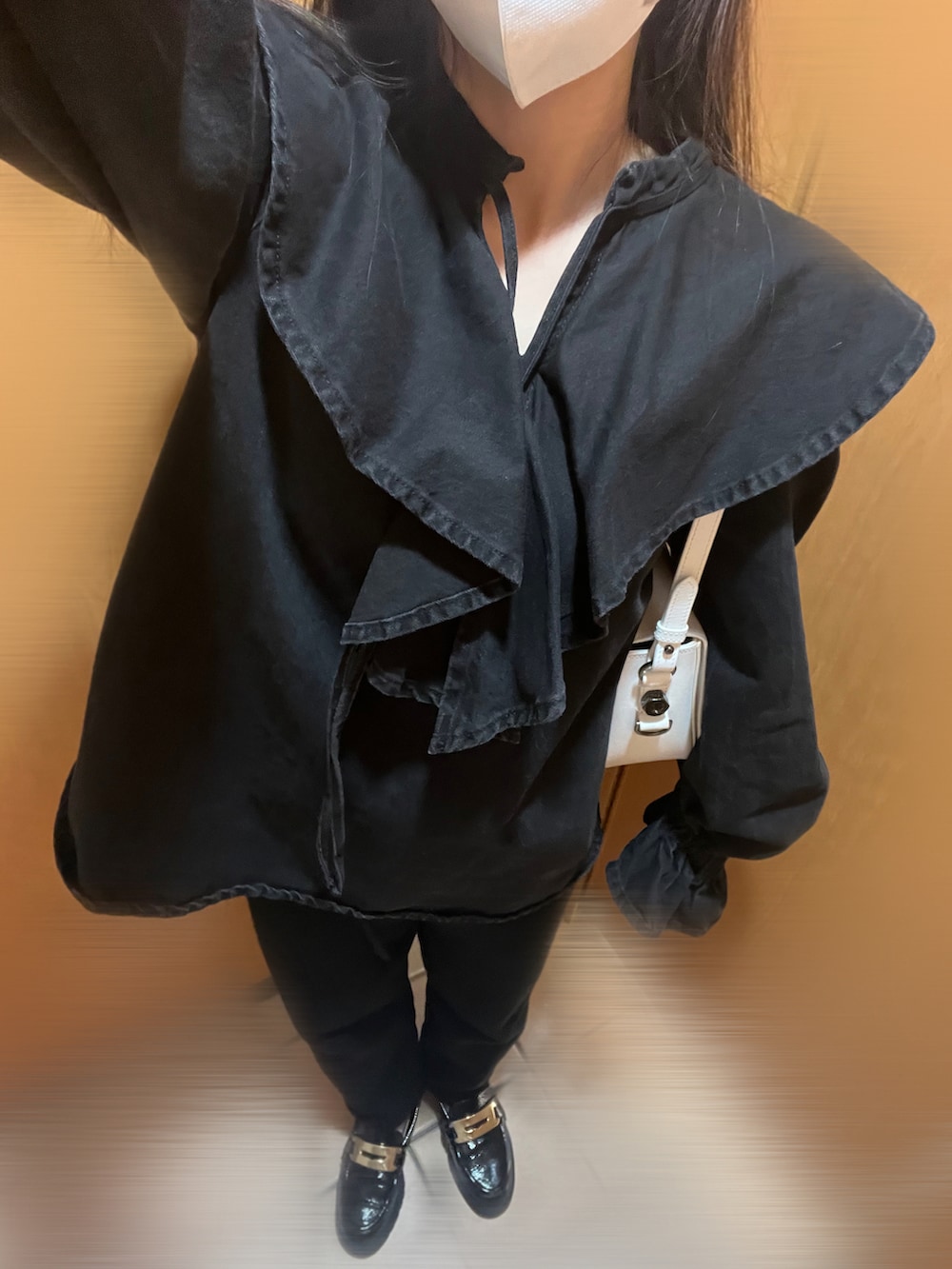 ホワイト系のショルダーバッグ、ブラック系のローファー、ブラック系のパンツを着用したレディースの秋コーディネートの2枚目の写真