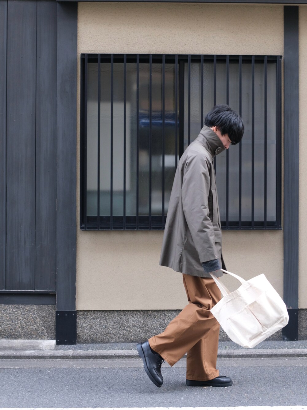 グリーン系のジャケット/アウター、ブラウン系のチノパンツ、ベージュ系のトートバッグを着用したメンズの春コーディネートの2枚目の写真