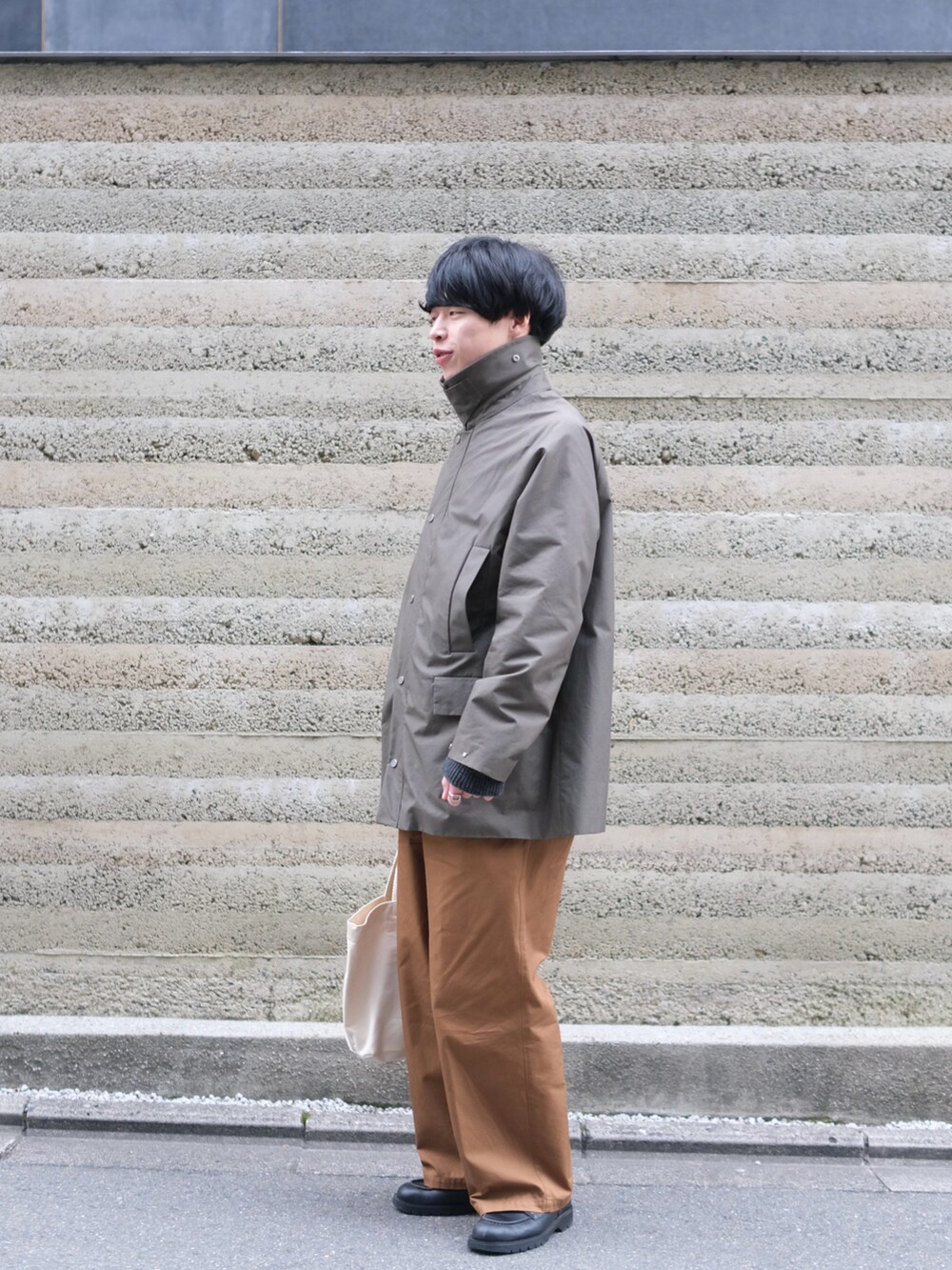 グリーン系のジャケット/アウター、ブラウン系のチノパンツ、ベージュ系のトートバッグを着用したメンズの春コーディネートの3枚目の写真