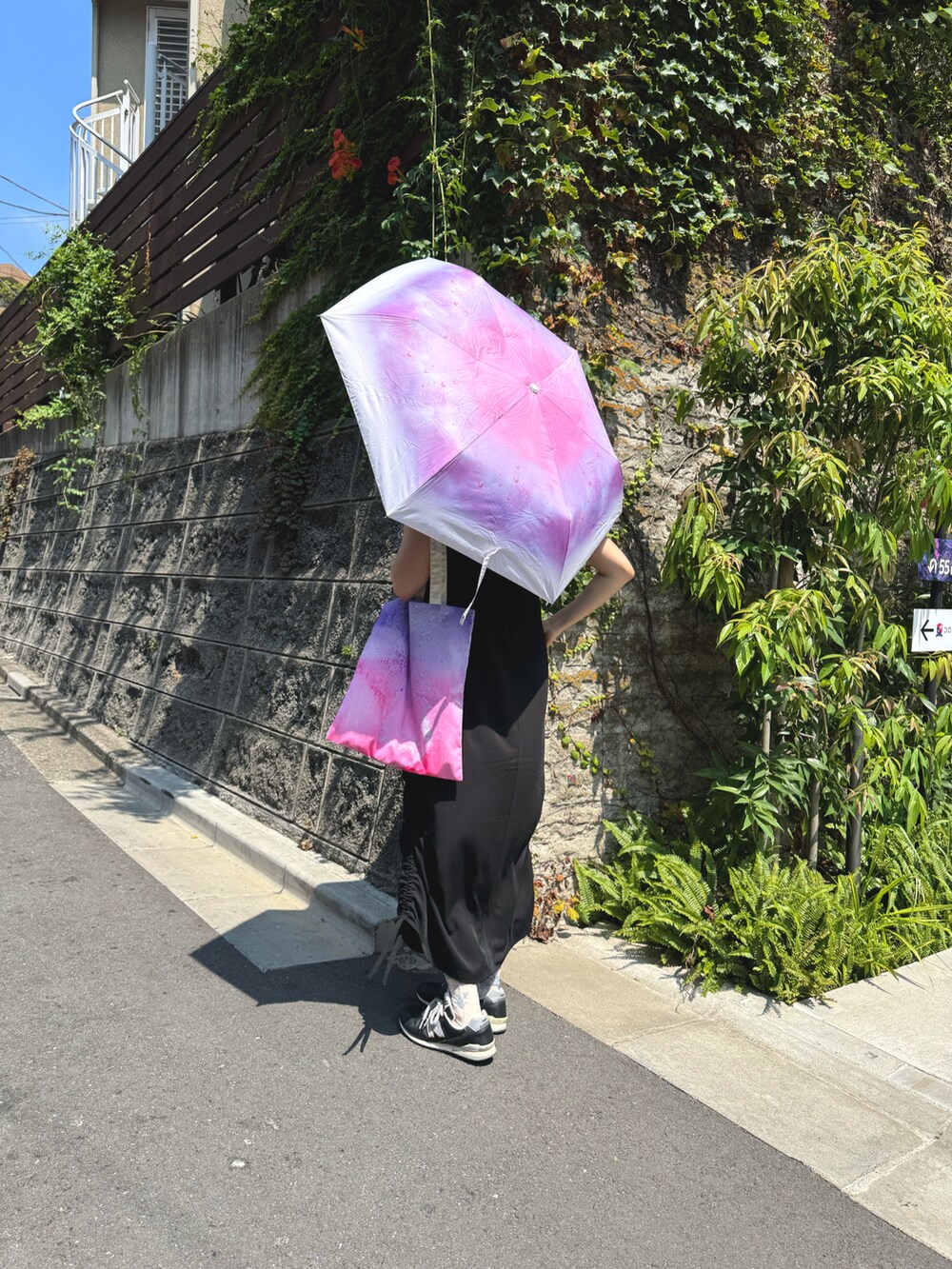 ピンク系のトートバッグ、ピンク系の折りたたみ傘を着用したレディースの夏コーディネートの2枚目の写真