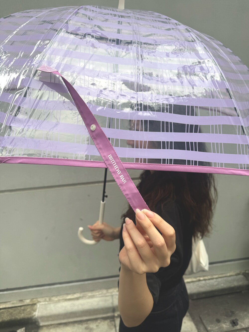 ホワイト系のトートバッグ、パープル系の長傘を着用したレディースの夏コーディネートの3枚目の写真