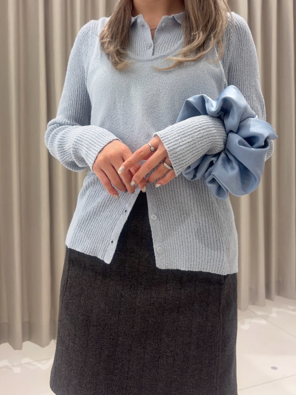 グレー系のハンドバッグ、ブラウン系のスカート、ブルー系のニット/セーターを着用したレディースの春コーディネートの3枚目の写真