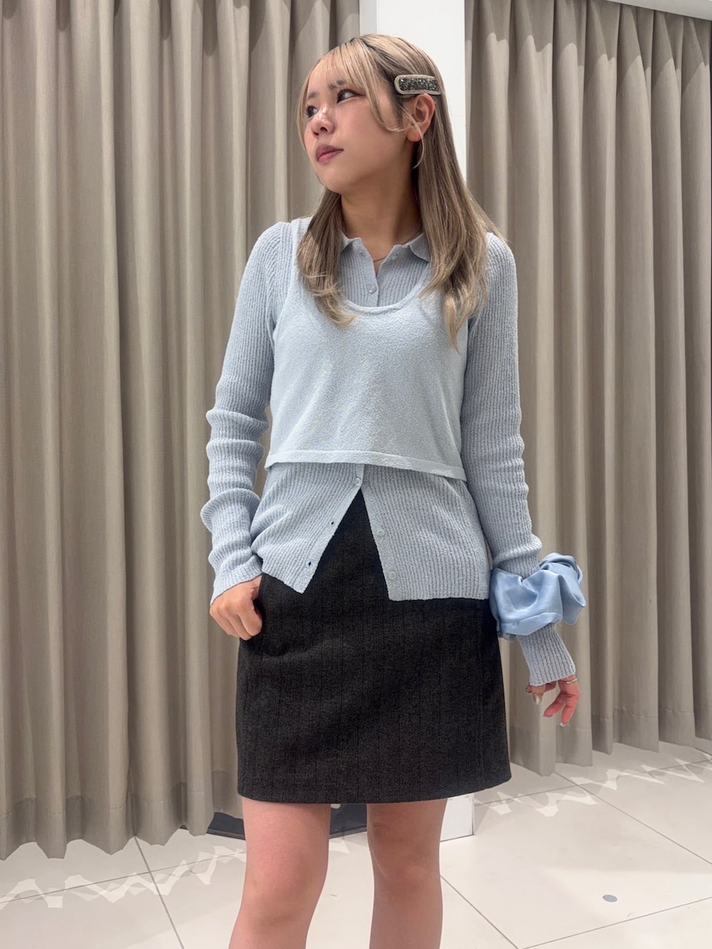 グレー系のハンドバッグ、ブラウン系のスカート、ブルー系のニット/セーターを着用したレディースの春コーディネートの2枚目の写真