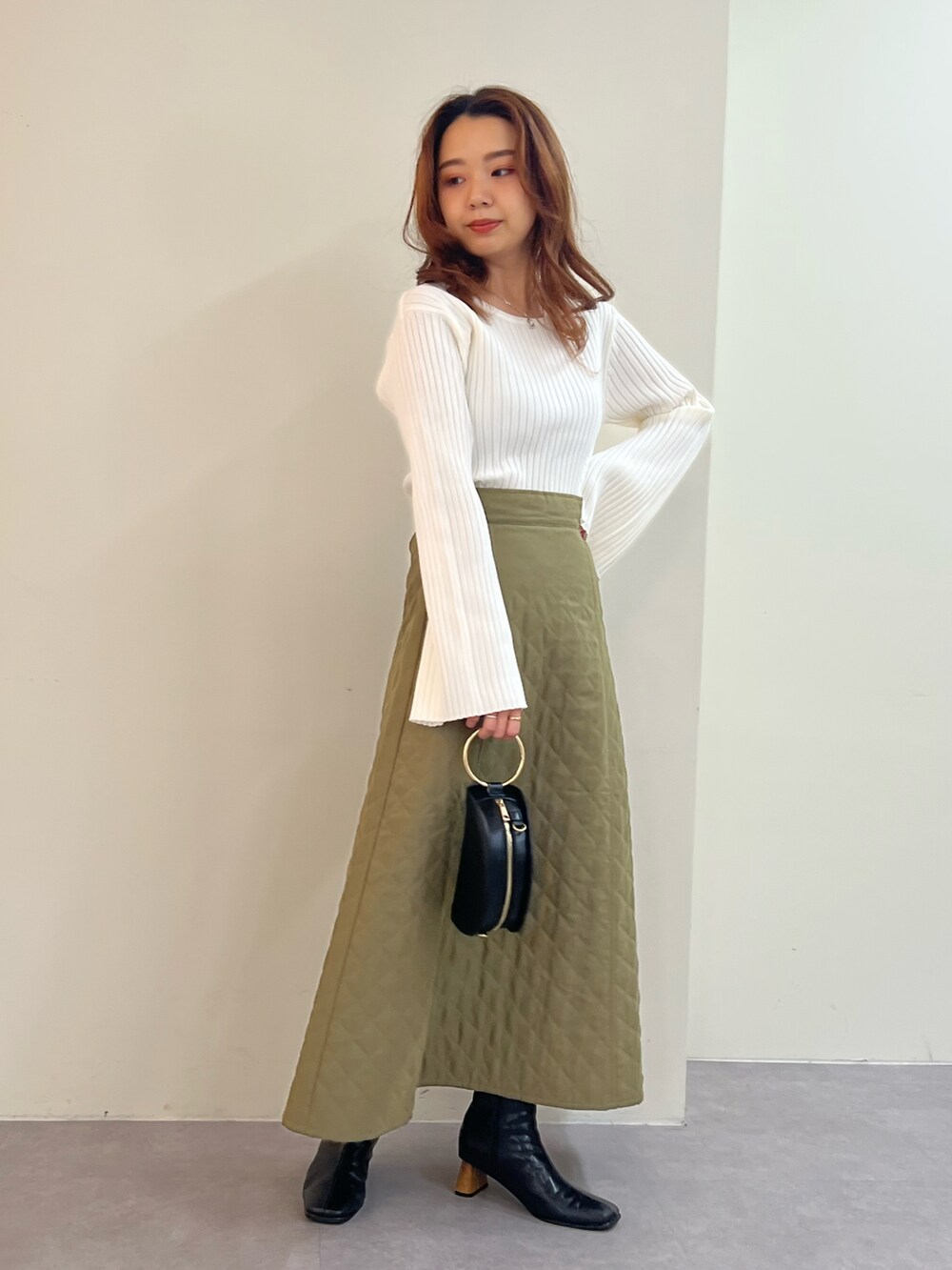 ホワイト系のニット/セーター、グリーン系のスカート、ブラウン系のブーツを着用したレディースの秋コーディネートの2枚目の写真
