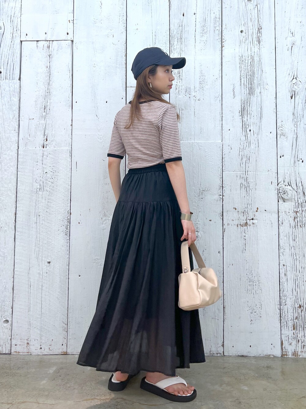 ブラウン系のTシャツ/カットソー、ホワイト系のサンダル、ベージュ系のショルダーバッグを着用したレディースの夏コーディネートの2枚目の写真