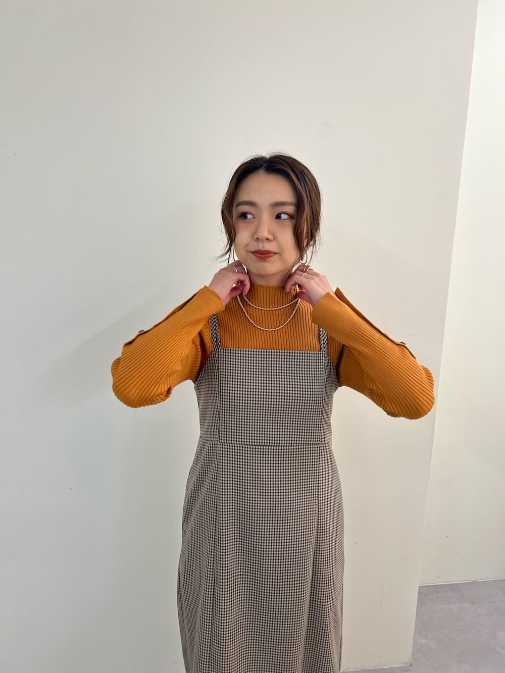 オレンジ系のニット/セーター、ブラウン系のブーツ、その他のワンピースを着用したレディースの冬コーディネートの2枚目の写真