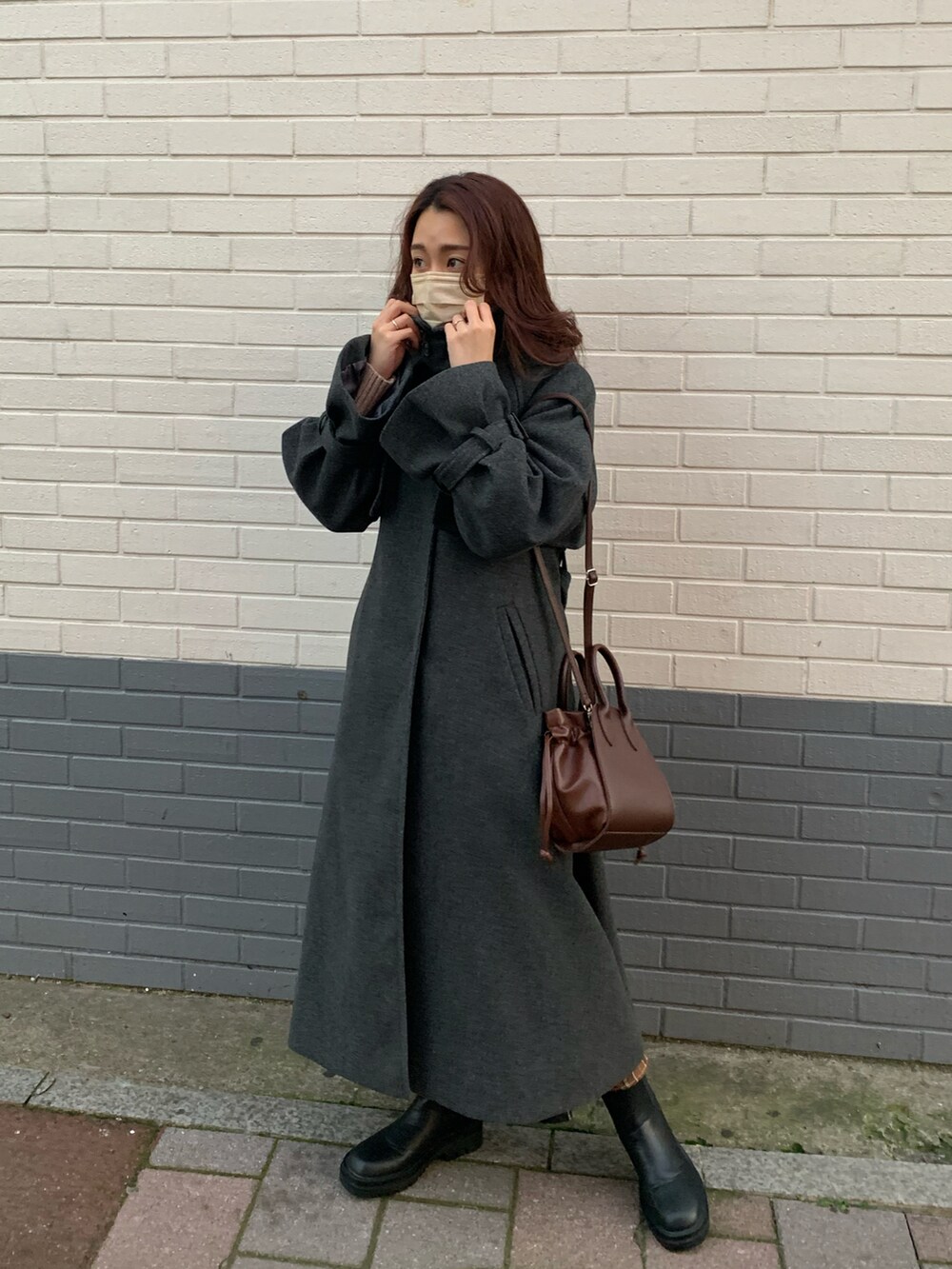 グレー系のチェスターコート、ブラック系のショルダーバッグ、ブラック系のスカートを着用したレディースの冬コーディネートの2枚目の写真