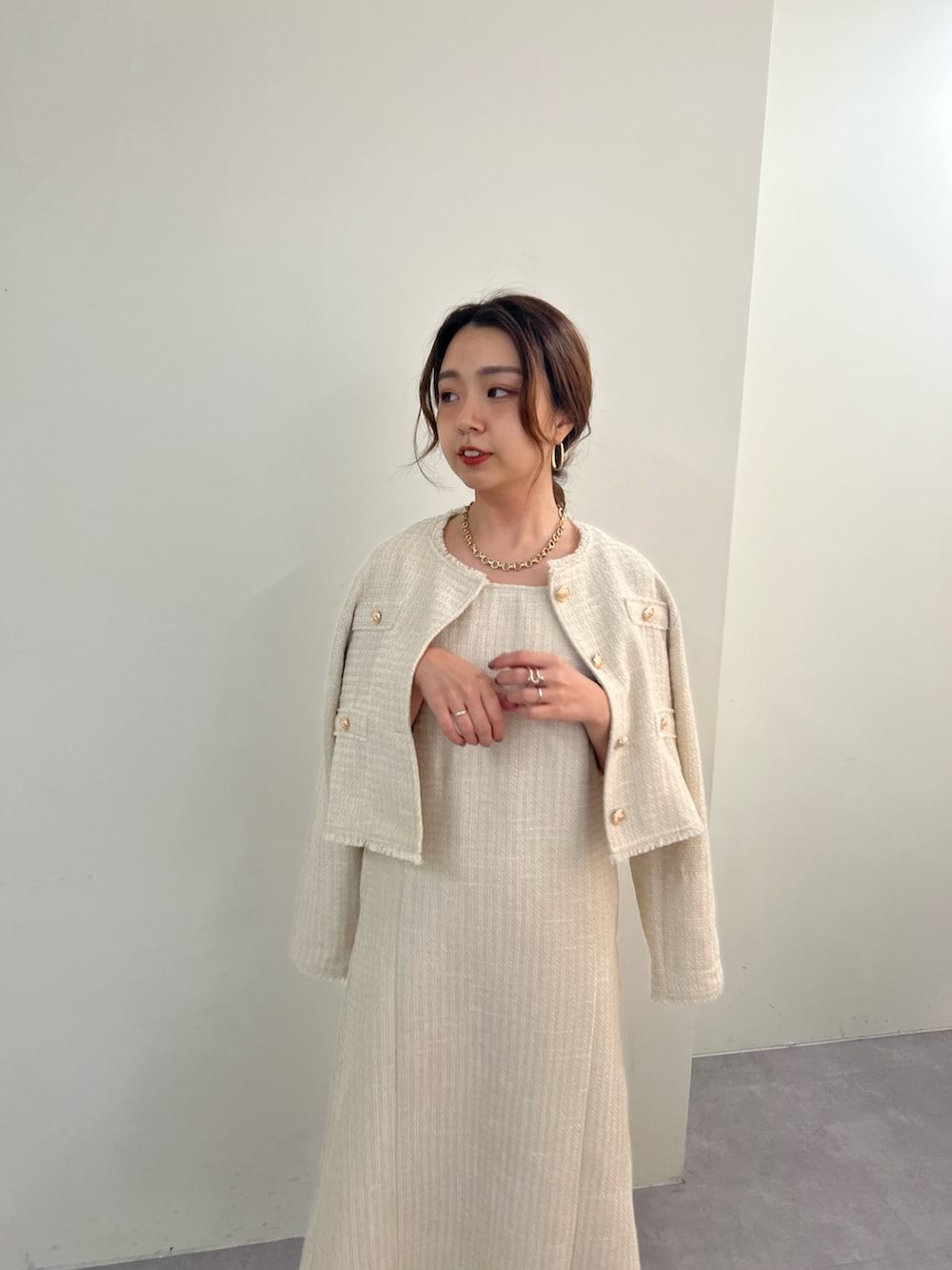 ベージュ系のノーカラージャケット、ベージュ系のジャンパースカート、ブラウン系のブーツを着用したレディースの秋コーディネートの2枚目の写真