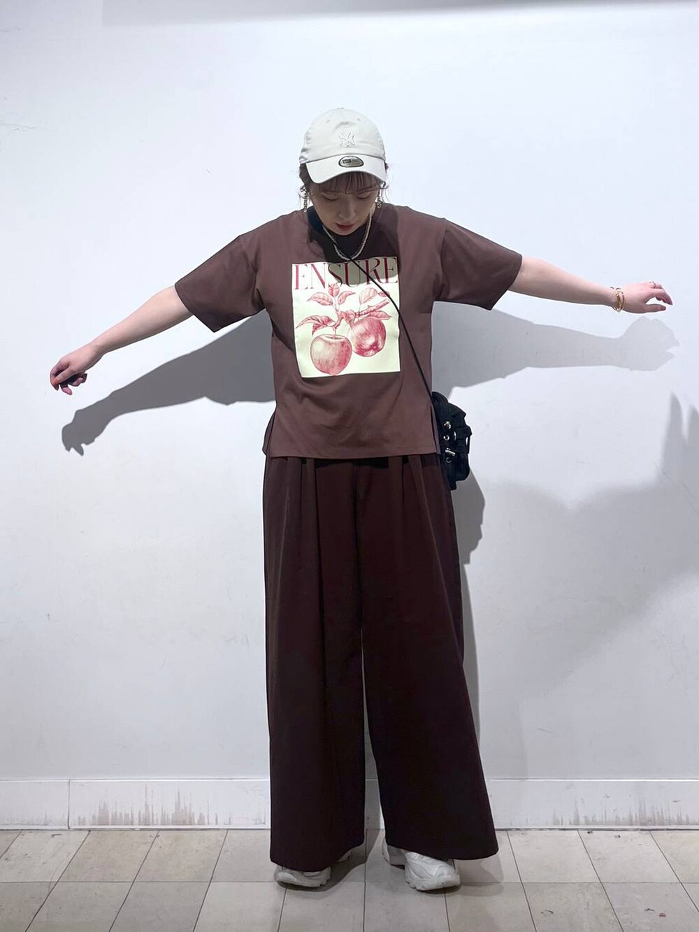 ブラウン系のTシャツ/カットソー、ホワイト系のタンクトップ、ブラック系のショルダーバッグを着用したレディースの夏コーディネートの2枚目の写真