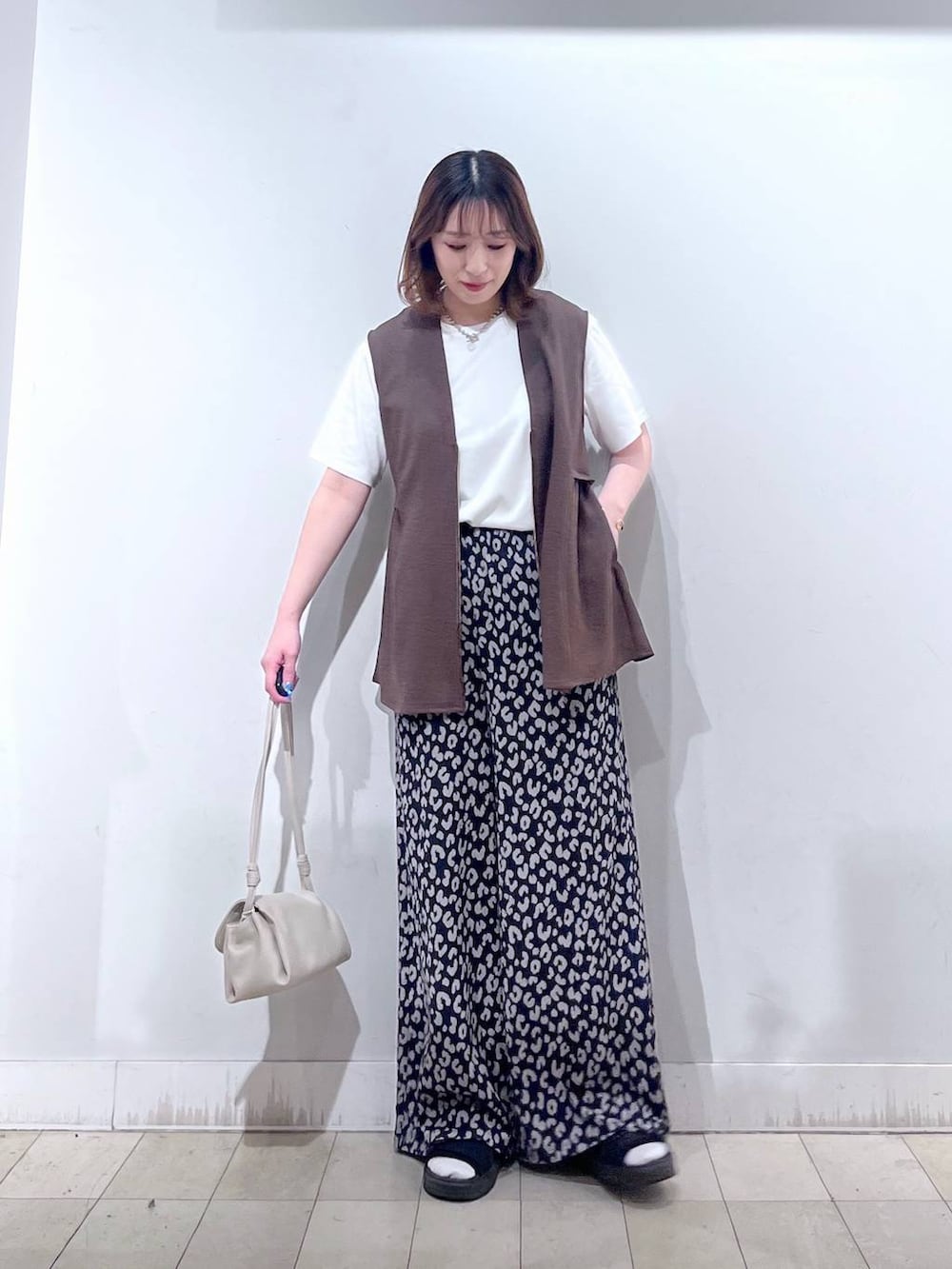ベージュ系のショルダーバッグ、ブラウン系のベスト、その他のその他パンツを着用したレディースの夏コーディネートの3枚目の写真