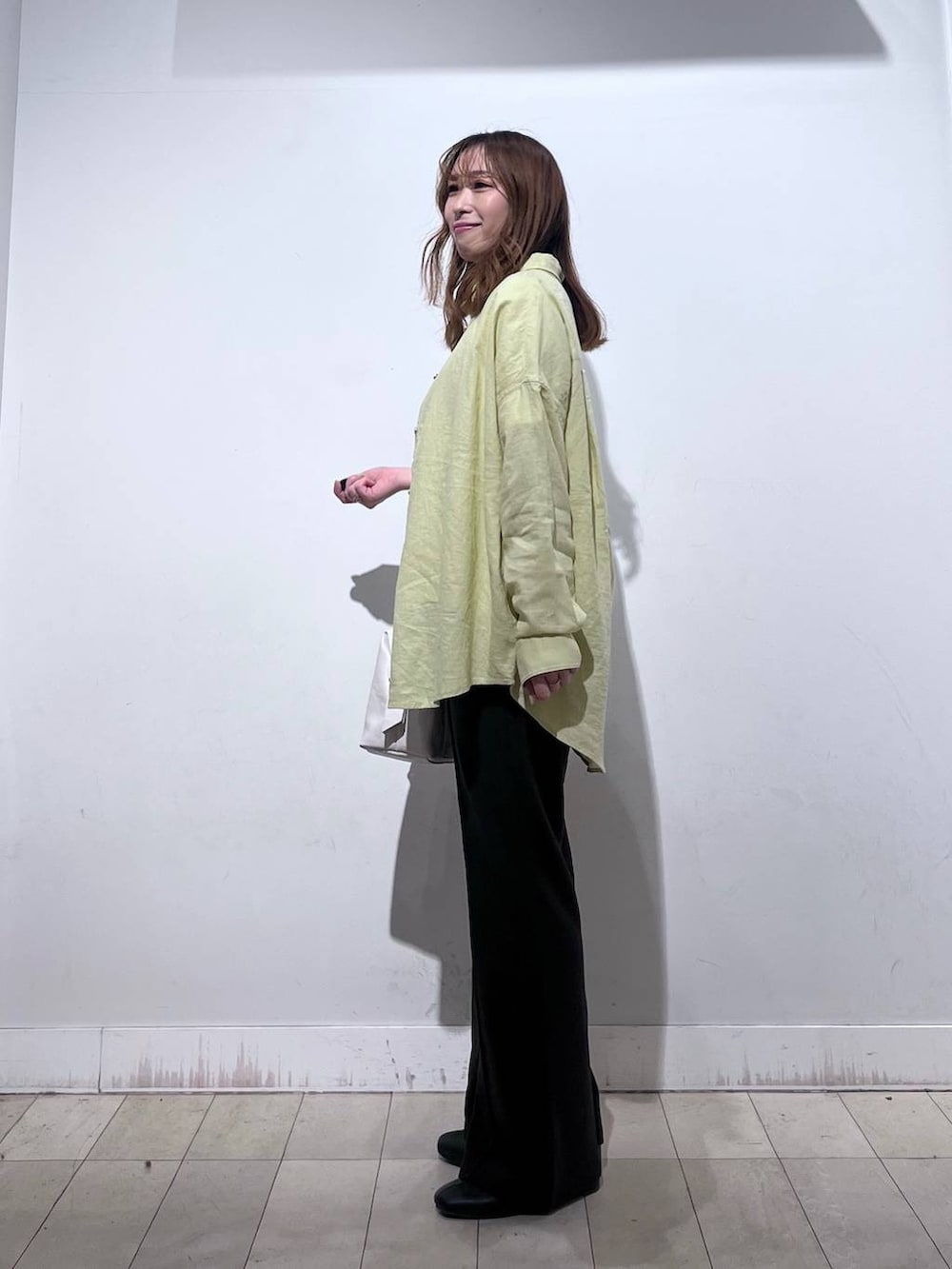 ホワイト系のボストンバッグ、ブラック系のブーツ、イエロー系のシャツ/ブラウスを着用したレディースの春コーディネートの2枚目の写真