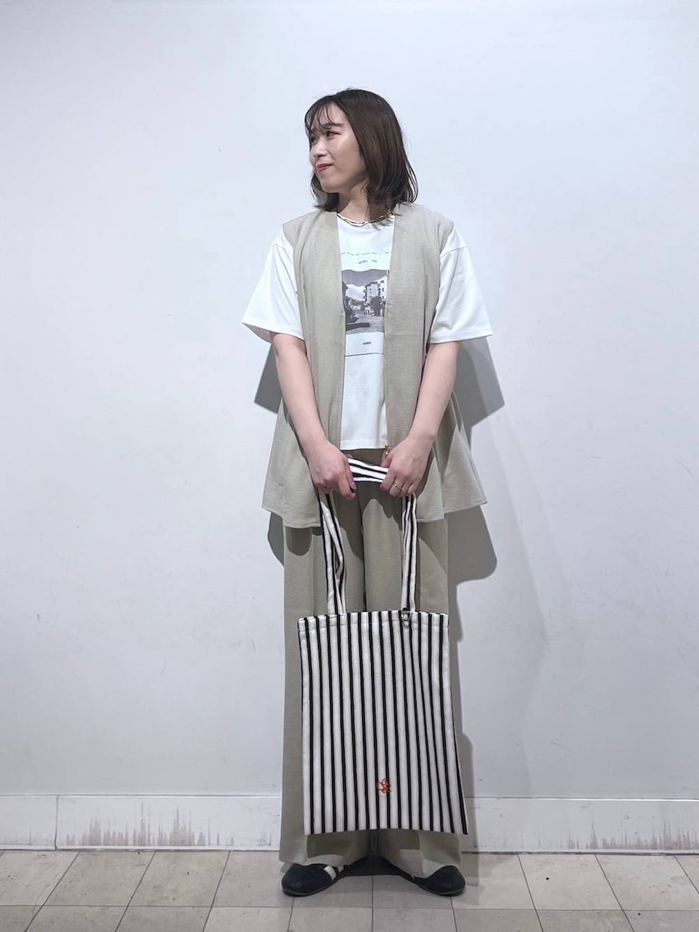 ホワイト系のトートバッグ、ベージュ系のベスト、ベージュ系のその他パンツを着用したレディースの夏コーディネートの3枚目の写真