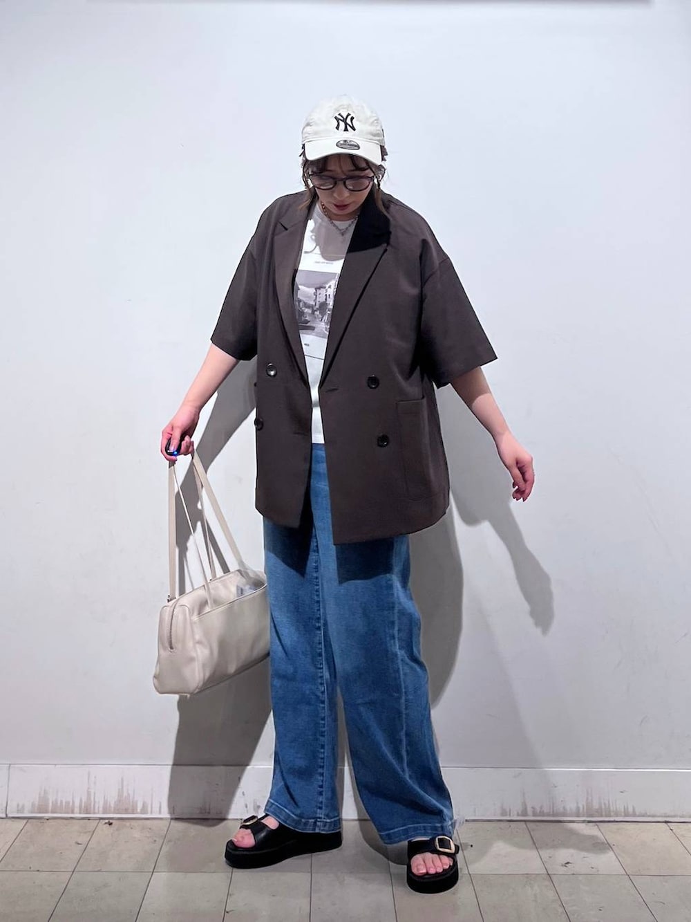 ブルー系のデニムパンツ、ホワイト系のTシャツ/カットソー、ベージュ系のショルダーバッグを着用したレディースの春コーディネートの5枚目の写真