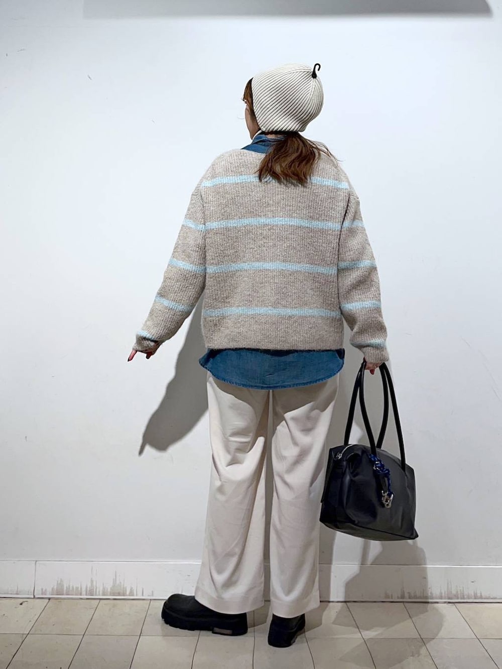 ブラック系のボストンバッグ、ブルー系のシャツ/ブラウス、ベージュ系のニット/セーターを着用したレディースの冬コーディネートの3枚目の写真