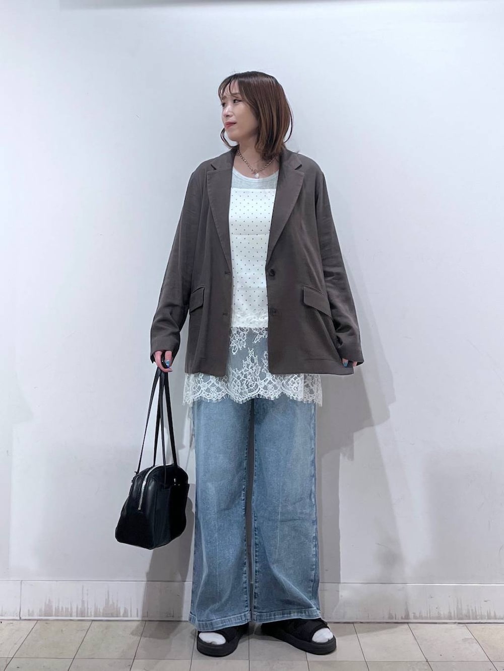 ブルー系のデニムパンツ、ブラウン系のテーラードジャケット、ホワイト系のキャミソールを着用したレディースの夏コーディネートの7枚目の写真