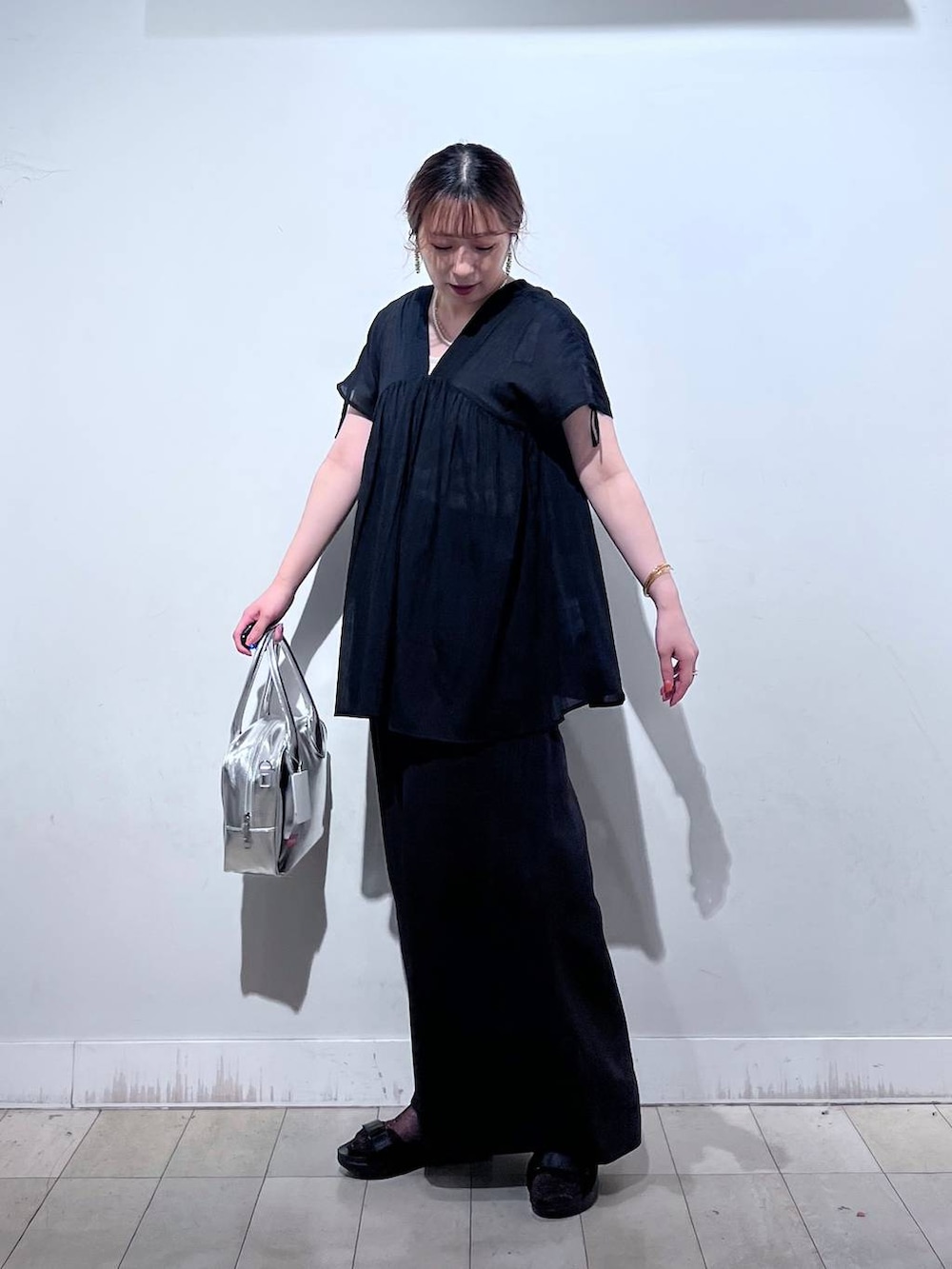 グレー系のボストンバッグ、ブラック系のサンダル、ブラック系のシャツ/ブラウスを着用したレディースの夏コーディネートの2枚目の写真