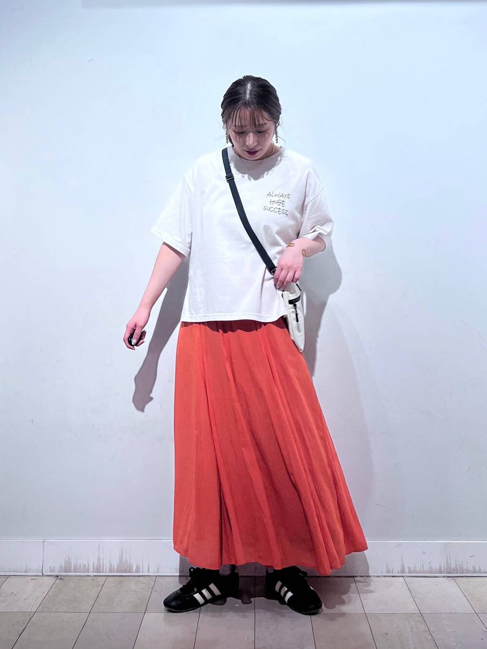 オレンジ系のスカート、ベージュ系のTシャツ/カットソー、ホワイト系のタンクトップを着用したレディースの夏コーディネートの3枚目の写真