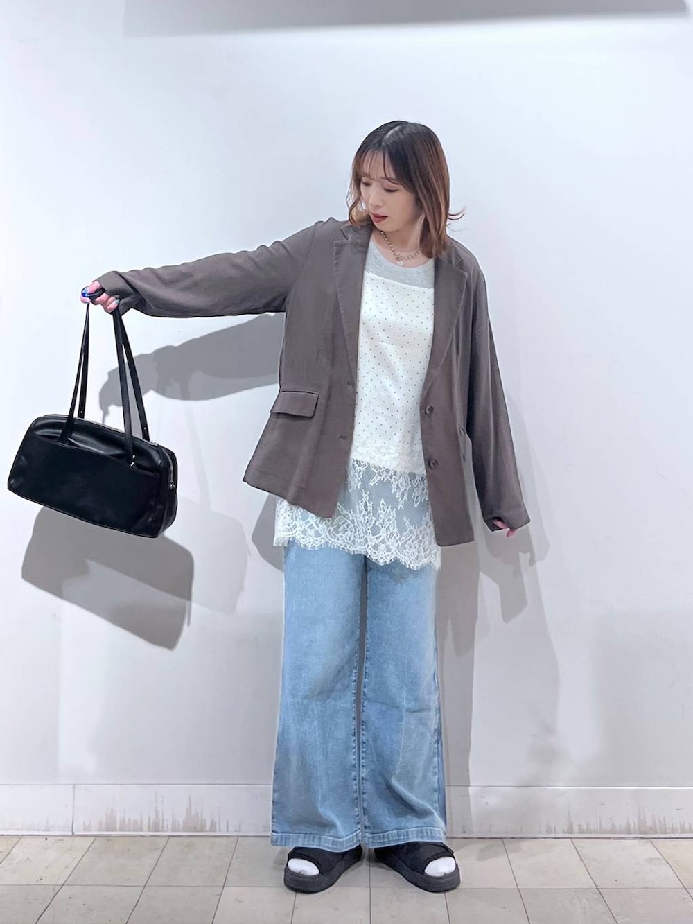 ブルー系のデニムパンツ、ブラウン系のテーラードジャケット、ホワイト系のキャミソールを着用したレディースの夏コーディネートの2枚目の写真