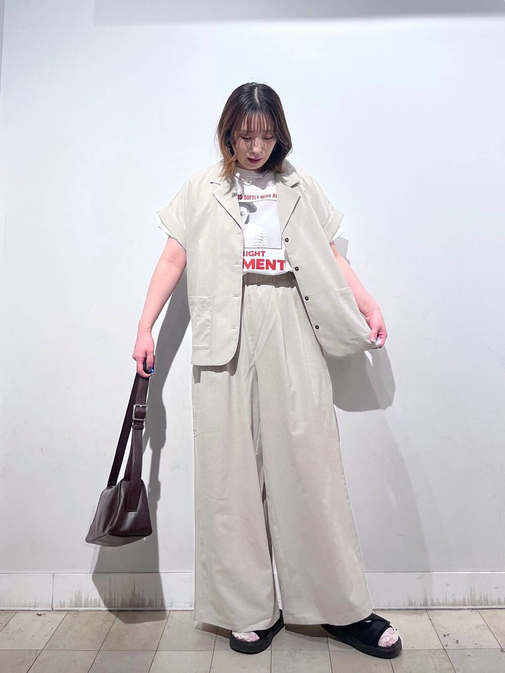 ブラウン系のショルダーバッグ、ホワイト系のTシャツ/カットソー、ブラック系のサンダルを着用したレディースの春コーディネートの6枚目の写真