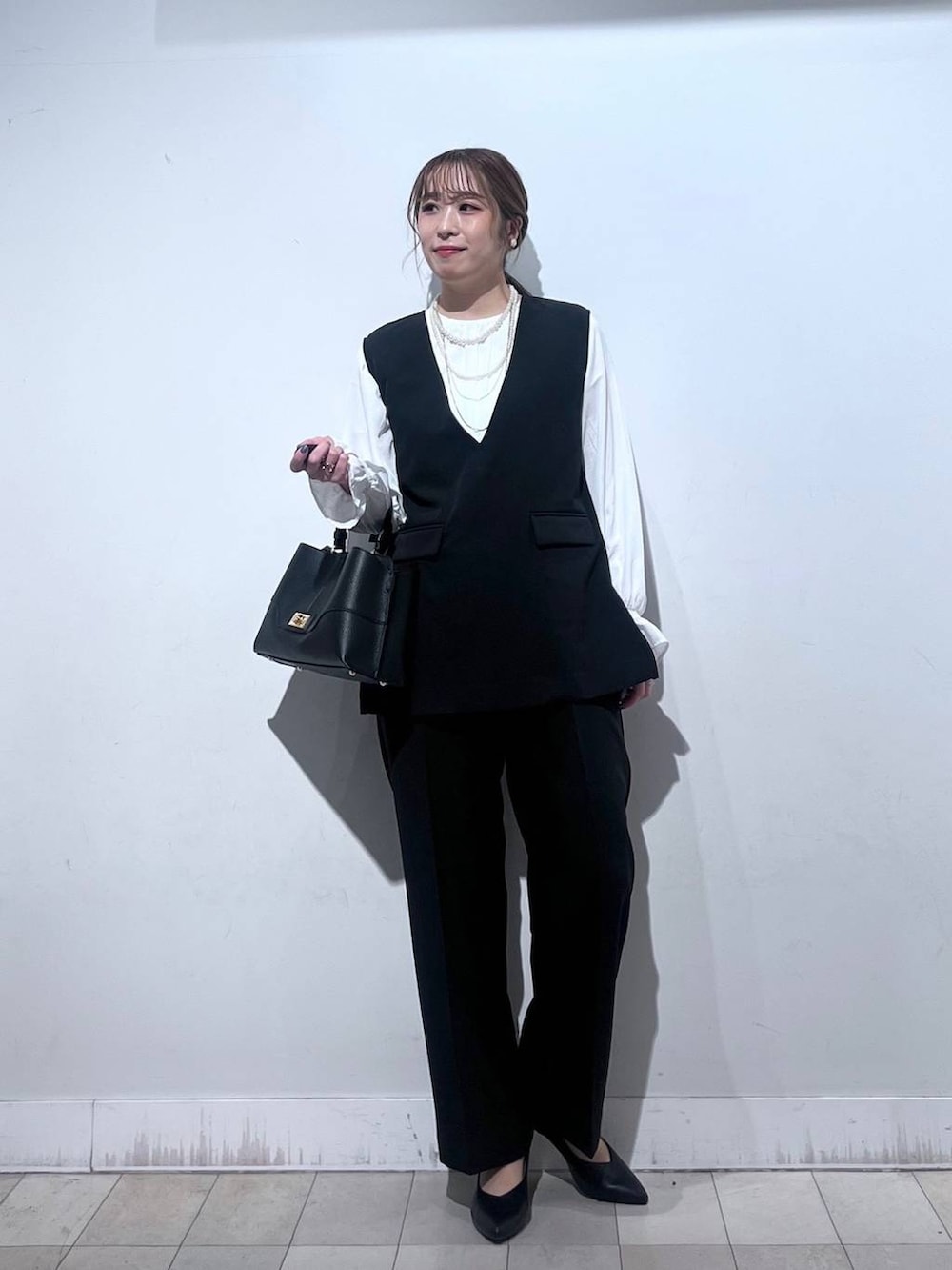 ブラック系のパンプス、ブルー系のセットアップ、ブラック系のショルダーバッグを着用したレディースの冬コーディネートの8枚目の写真