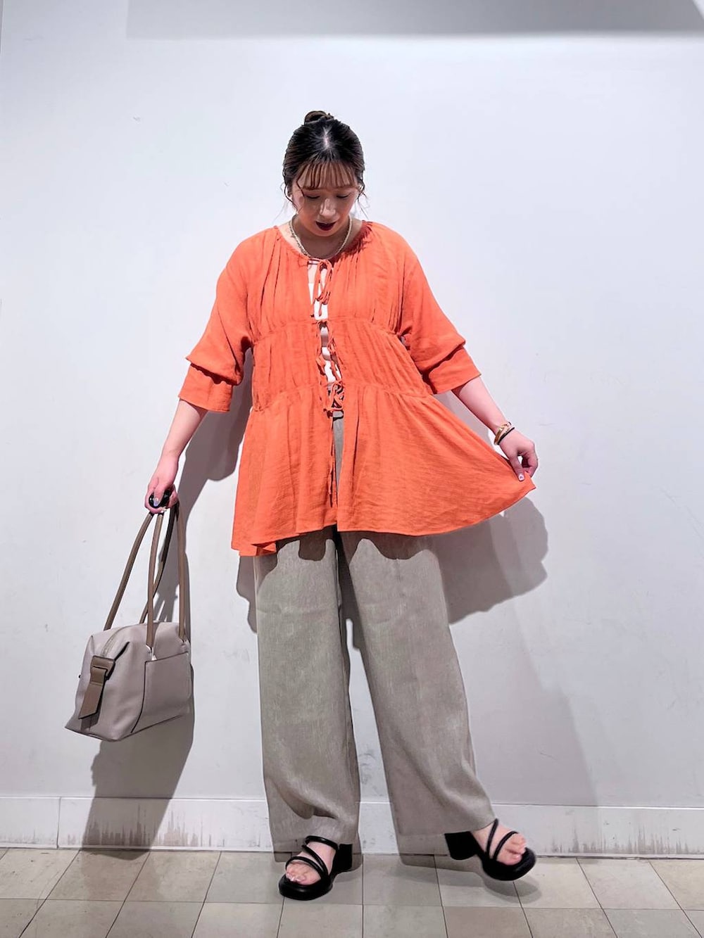 オレンジ系のシャツ/ブラウス、ホワイト系のタンクトップ、ベージュ系のボストンバッグを着用したレディースの秋コーディネートの2枚目の写真