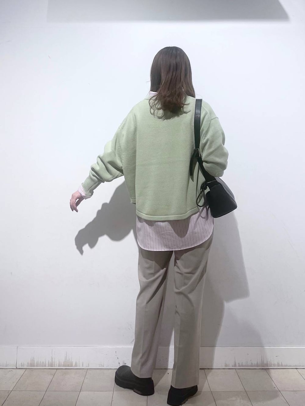 グリーン系のニット/セーター、ピンク系のシャツ/ブラウス、ベージュ系のスラックスを着用したレディースの春コーディネートの6枚目の写真