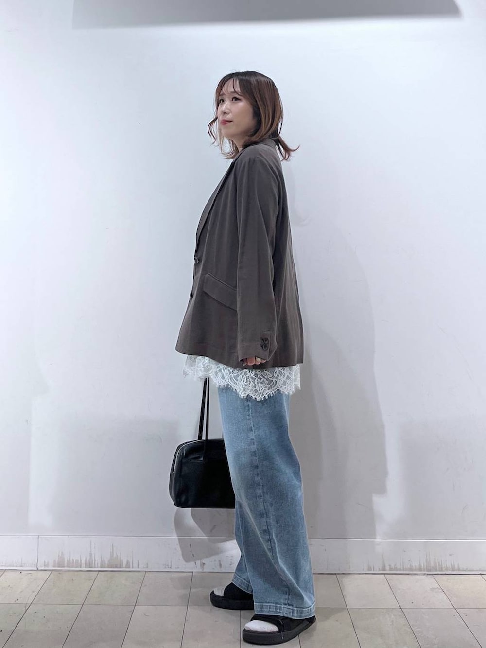 ブルー系のデニムパンツ、ブラウン系のテーラードジャケット、ホワイト系のキャミソールを着用したレディースの夏コーディネートの3枚目の写真