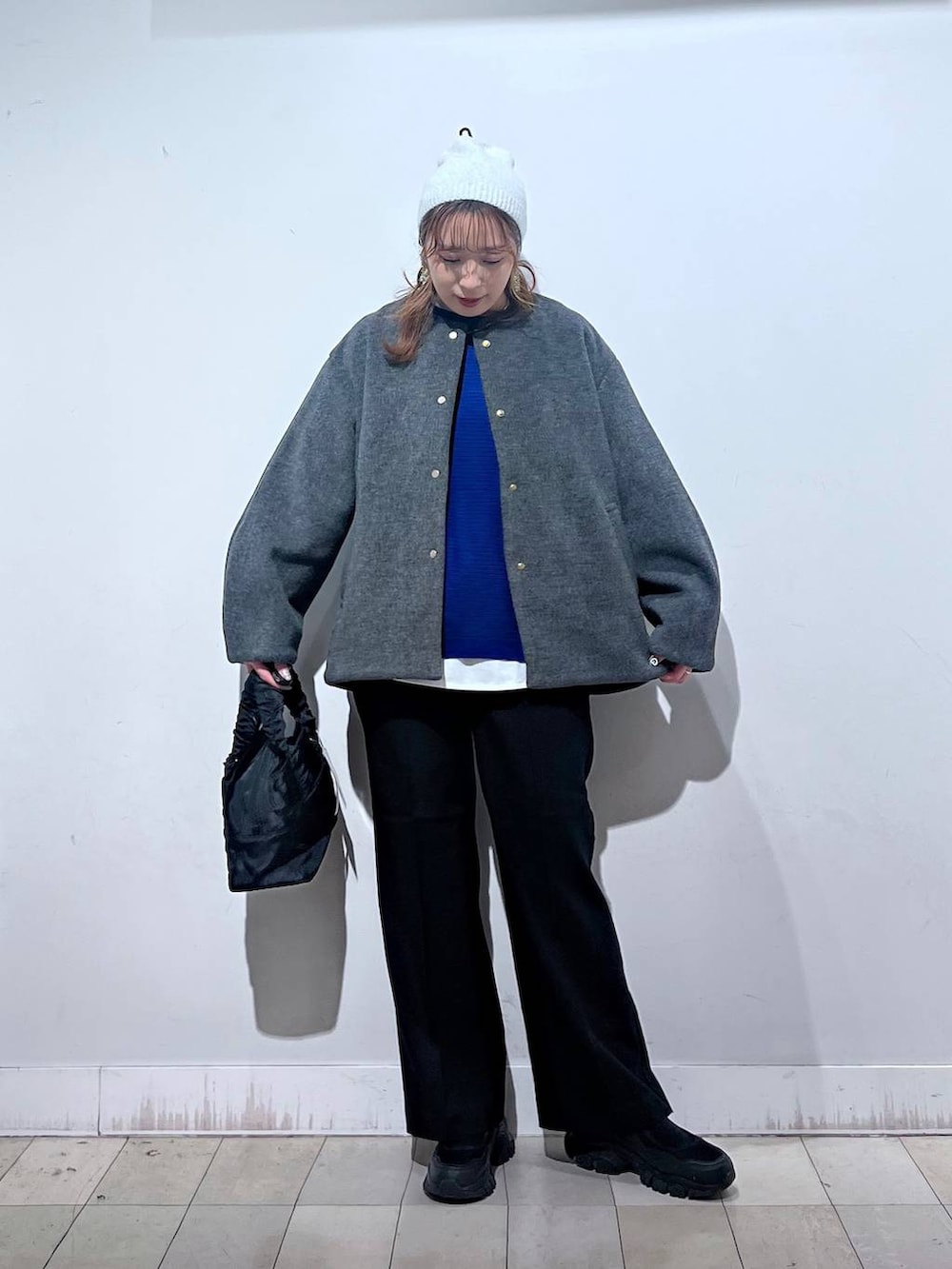 ブラック系のスニーカー、ブラック系のショルダーバッグ、グレー系のノーカラーコートを着用したレディースの秋コーディネートの4枚目の写真