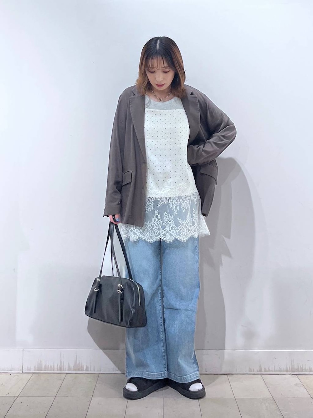 ブルー系のデニムパンツ、ブラウン系のテーラードジャケット、ホワイト系のキャミソールを着用したレディースの夏コーディネートの6枚目の写真