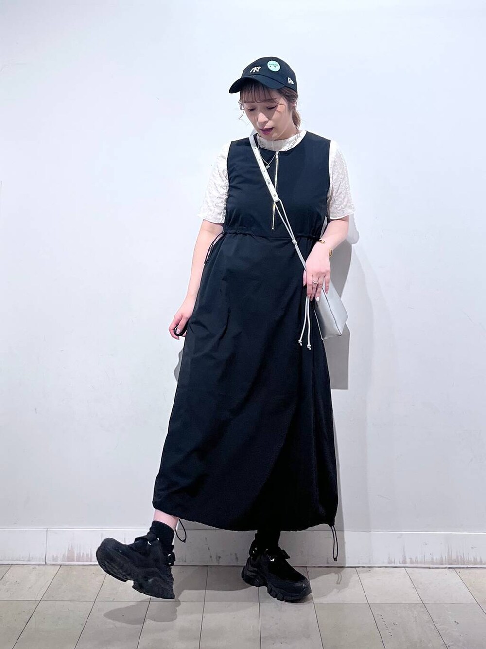 ブラック系のスニーカー、シルバー系のショルダーバッグ、ベージュ系のTシャツ/カットソーを着用したレディースの夏コーディネートの3枚目の写真