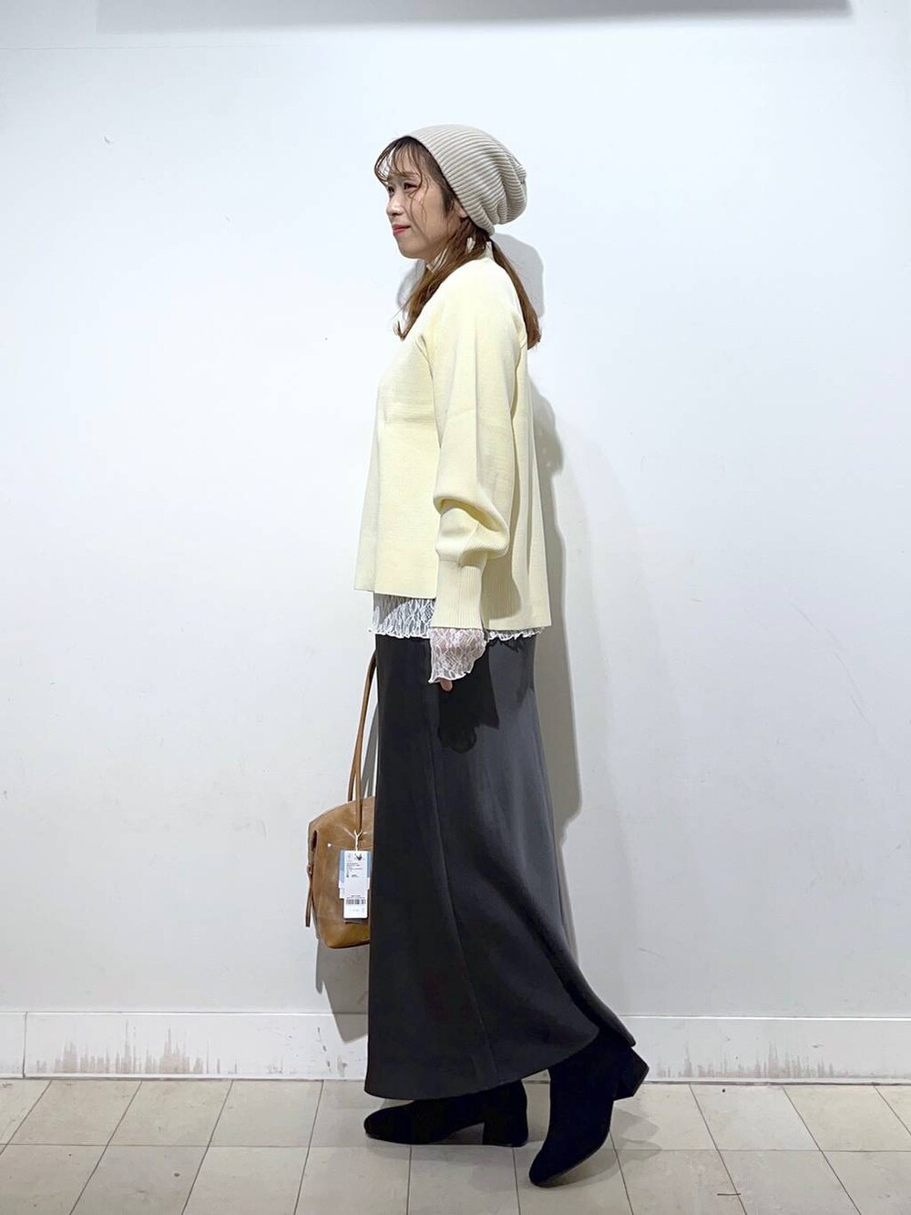 ブラウン系のボストンバッグ、ベージュ系のダウンジャケット/コート、ホワイト系のTシャツ/カットソーを着用したレディースの冬コーディネートの3枚目の写真