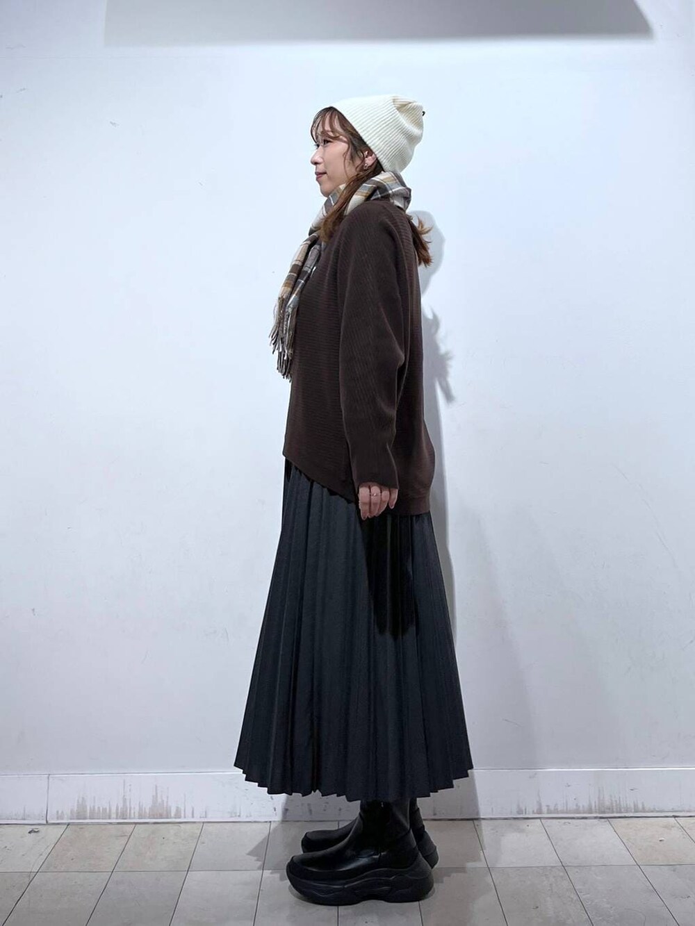 ブラック系のブーツ、グレー系のスカート、ブラウン系のマフラーを着用したレディースの冬コーディネートの3枚目の写真