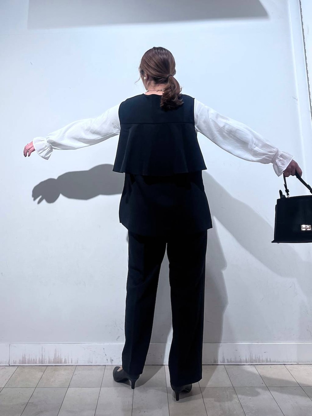 ブラック系のパンプス、ブルー系のセットアップ、ブラック系のショルダーバッグを着用したレディースの冬コーディネートの7枚目の写真