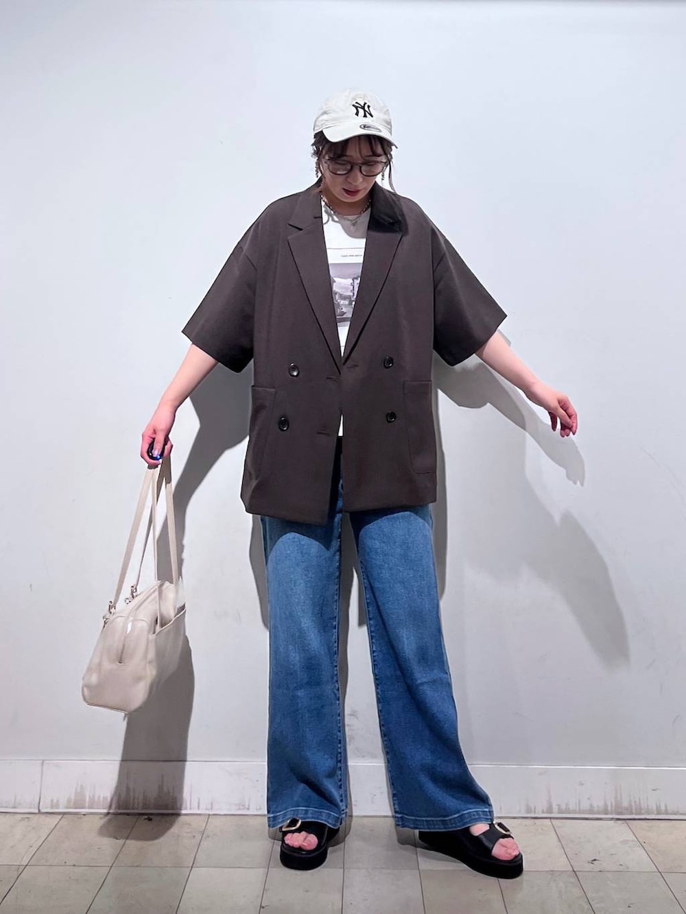 ブルー系のデニムパンツ、ホワイト系のTシャツ/カットソー、ベージュ系のショルダーバッグを着用したレディースの春コーディネートの8枚目の写真