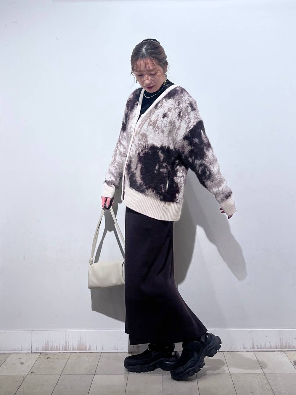 ブラック系のスニーカー、ブラック系のニット/セーター、ベージュ系のショルダーバッグを着用したレディースの秋コーディネートの5枚目の写真