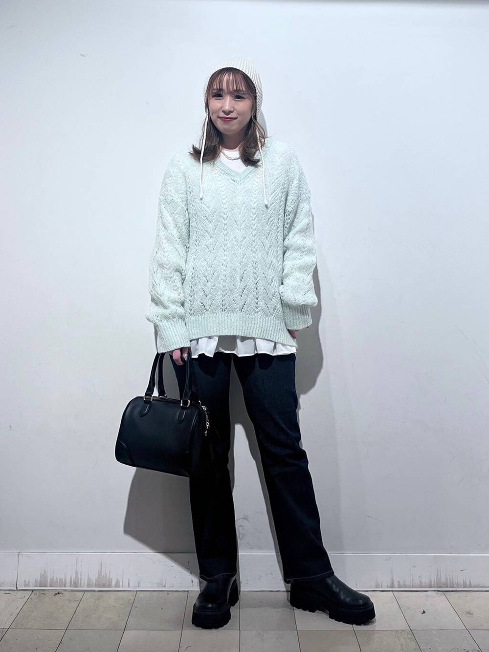 ブラック系のデニムパンツ、ホワイト系のTシャツ/カットソー、ブラック系のボストンバッグを着用したレディースの秋コーディネートの4枚目の写真