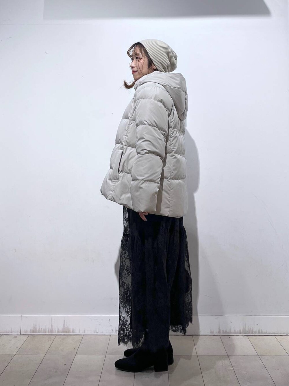 ブラウン系のショルダーバッグ、ベージュ系のダウンジャケット/コート、イエロー系のワンピースを着用したレディースの冬コーディネートの3枚目の写真