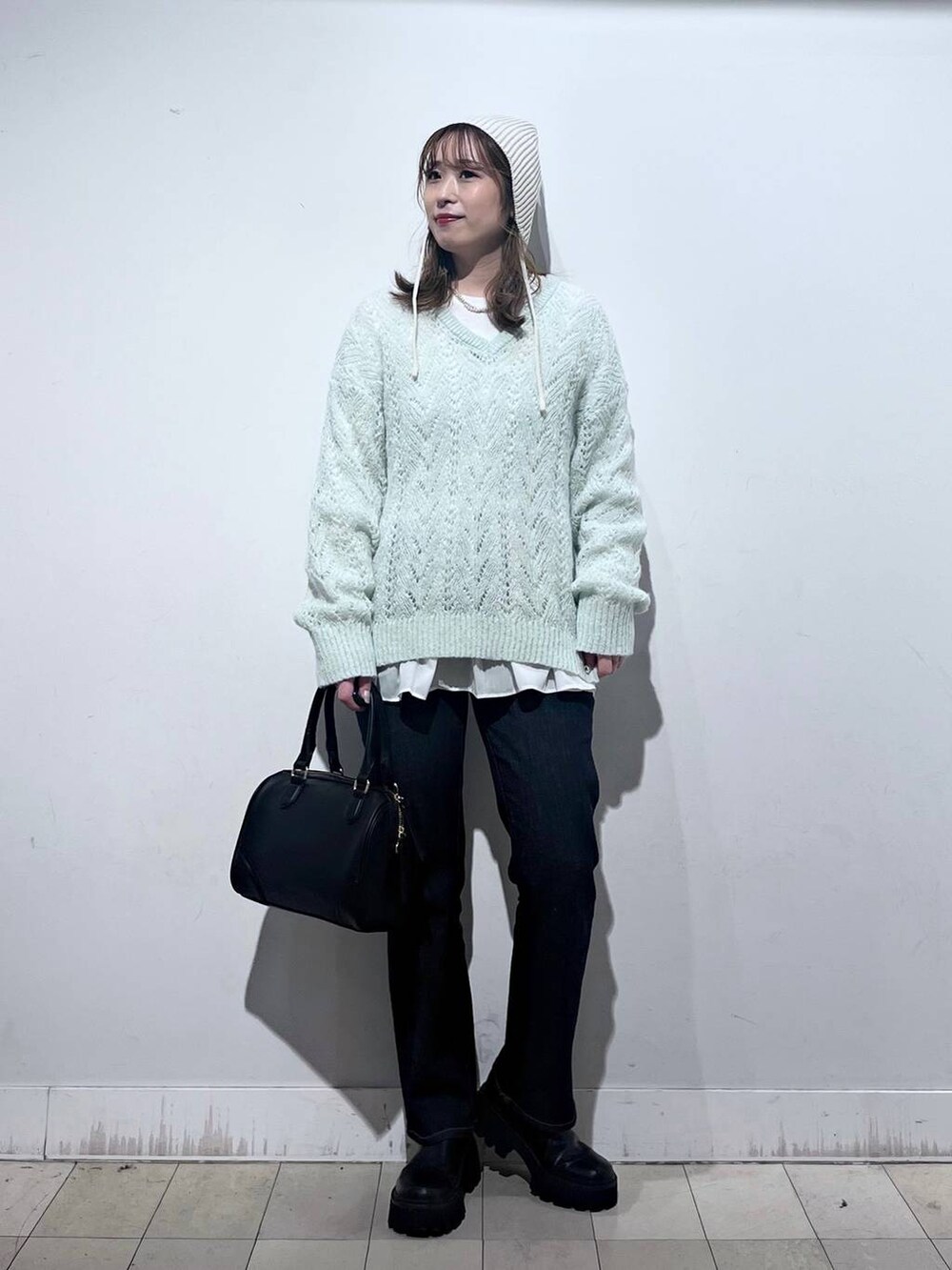 ブラック系のデニムパンツ、ホワイト系のTシャツ/カットソー、ブラック系のボストンバッグを着用したレディースの秋コーディネートの2枚目の写真