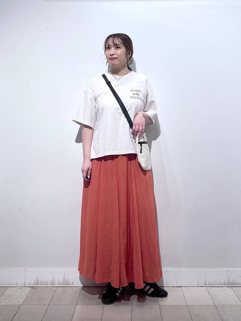 オレンジ系のスカート、ベージュ系のTシャツ/カットソー、ホワイト系のタンクトップを着用したレディースの夏コーディネートの5枚目の写真