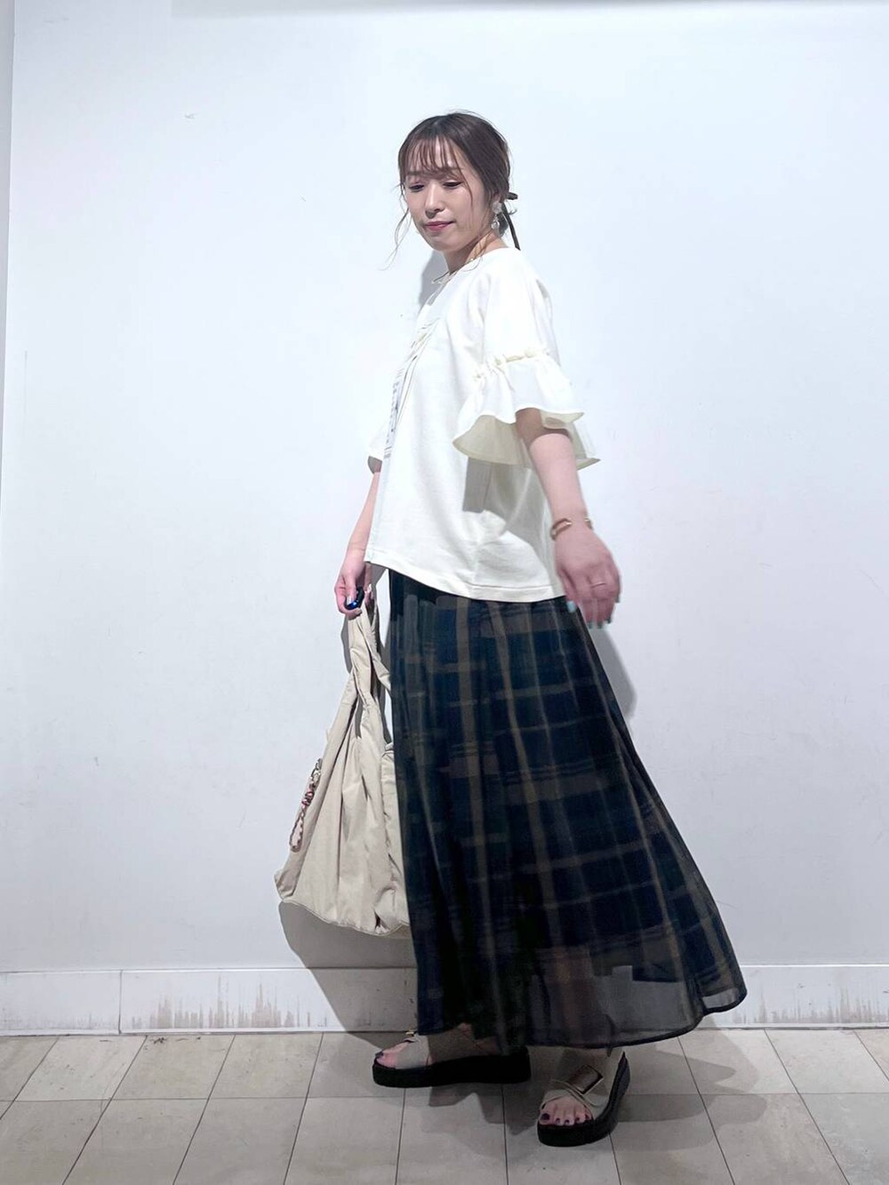 ホワイト系のタンクトップ、ベージュ系のトートバッグ、ベージュ系のサンダルを着用したレディースの秋コーディネートの3枚目の写真