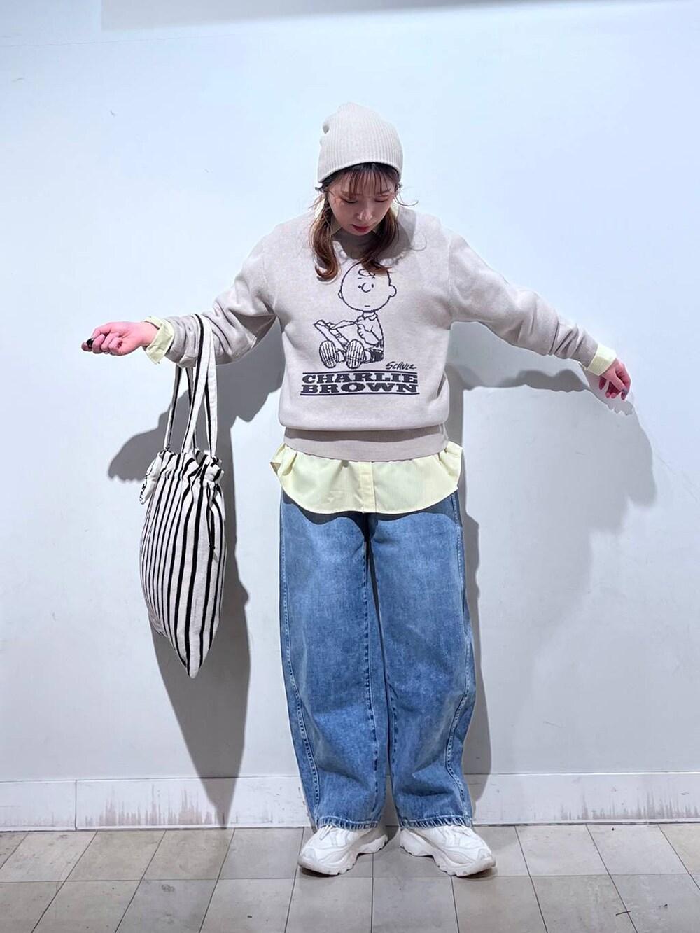 イエロー系のシャツ/ブラウス、ブルー系のデニムパンツ、ベージュ系のニット/セーターを着用したレディースの冬コーディネートの5枚目の写真