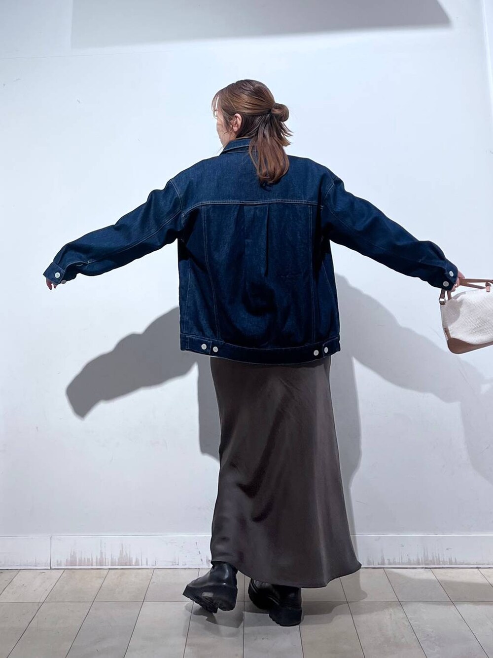 ホワイト系のショルダーバッグ、ブルー系のデニムジャケット、ブラウン系のスカートを着用したレディースの冬コーディネートの5枚目の写真