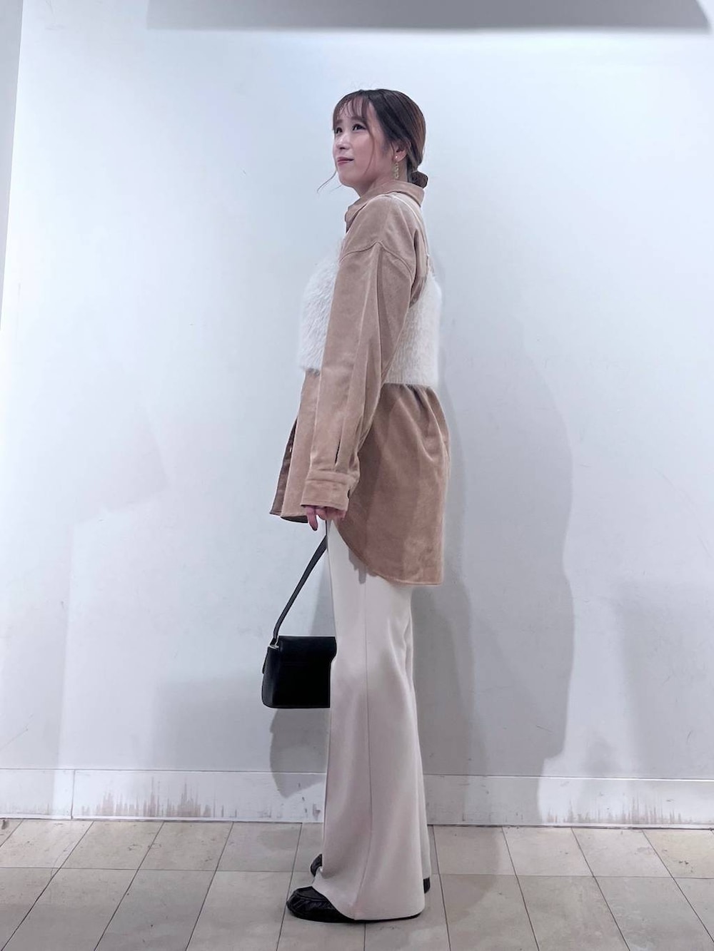 ベージュ系のその他パンツ、ホワイト系のベスト、ブラック系のショルダーバッグを着用したレディースの秋コーディネートの2枚目の写真