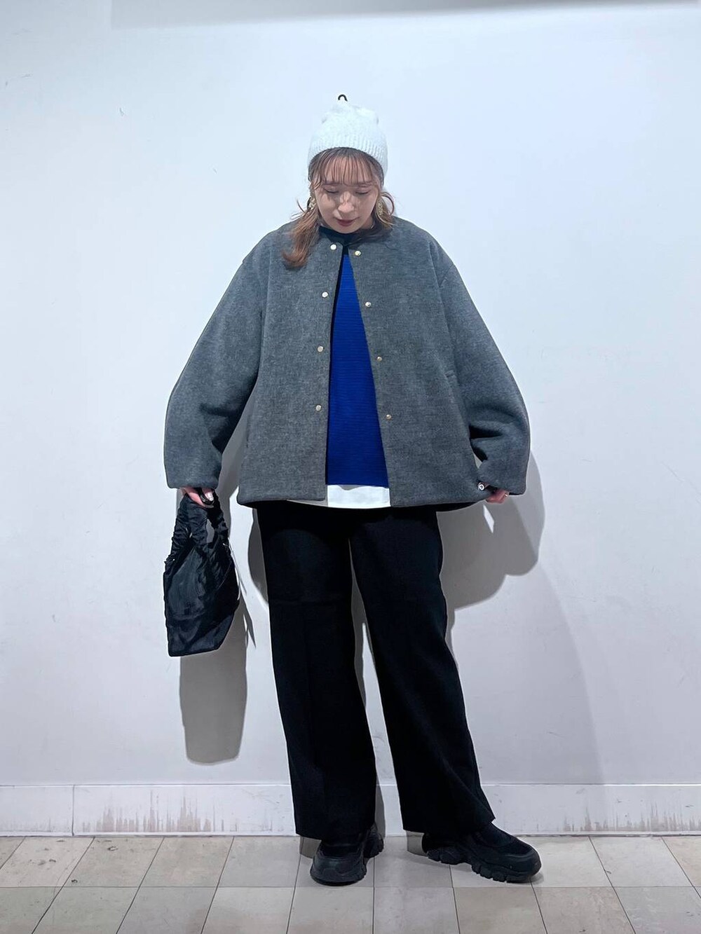 ブラック系のスニーカー、ブラック系のショルダーバッグ、グレー系のノーカラーコートを着用したレディースの秋コーディネートの7枚目の写真