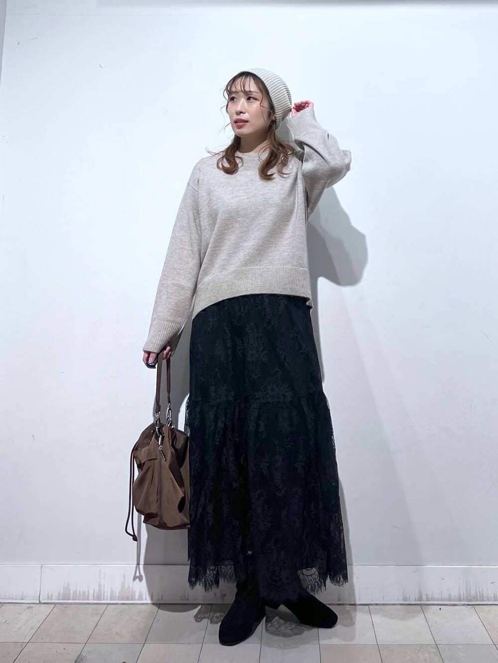 ブラウン系のショルダーバッグ、ベージュ系のダウンジャケット/コート、イエロー系のワンピースを着用したレディースの冬コーディネートの2枚目の写真