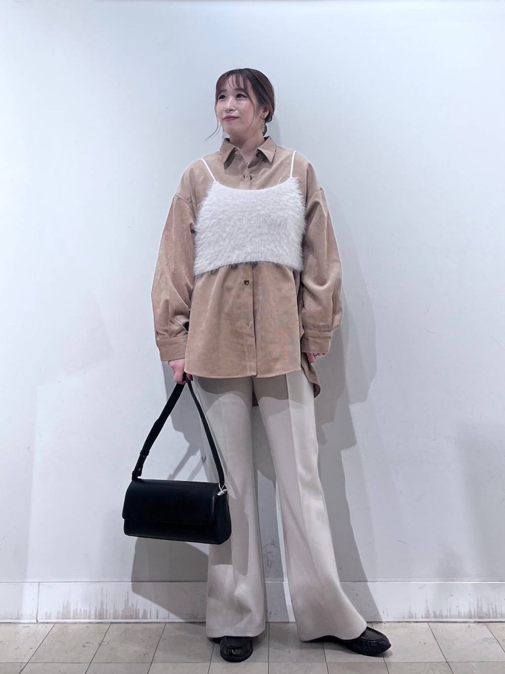 ベージュ系のその他パンツ、ホワイト系のベスト、ブラック系のショルダーバッグを着用したレディースの秋コーディネートの5枚目の写真