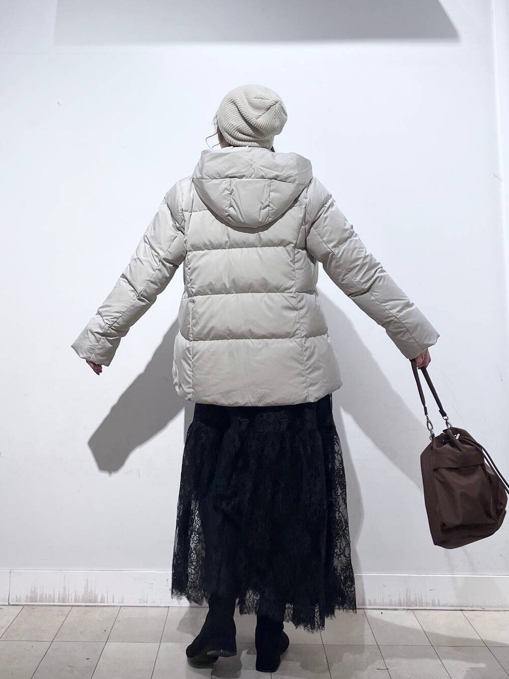 ブラウン系のショルダーバッグ、ベージュ系のダウンジャケット/コート、イエロー系のワンピースを着用したレディースの冬コーディネートの8枚目の写真